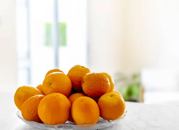 厨房桌子上的新鲜橘子放在盘子里 — 图库照片