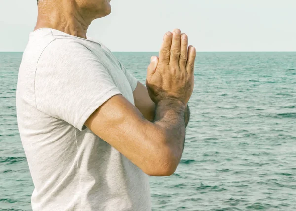 An adult man standing with palms in a gesture namaste by the sea. The concept of spirituality and self-awareness — Stock Photo, Image