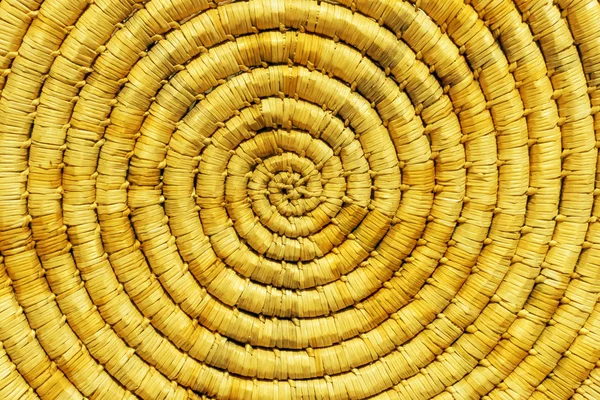 Handmade antique work weaving natural material yellow background. Spiral weaving or weaving in a circle