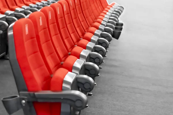 A row of red seats on the gray floor of the modern cinema hall. — Stock Photo, Image