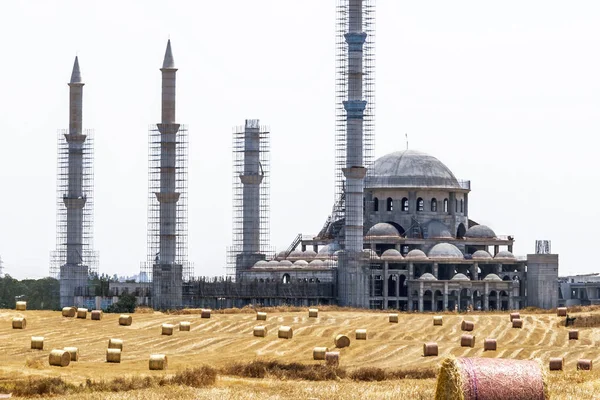 Όμορφο τοπίο στην Κύπρο. Στρογγυλές μπάλες άχυρο για ζωοτροφές με φόντο το τουρκικό Τζαμί υπό κατασκευή. — Φωτογραφία Αρχείου