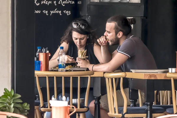 CYPRUS, NICOSIA - JUNE 10, 2019: Young couple eating in street outdoor restaurant. Man and woman enjoying fast food — Stock Photo, Image