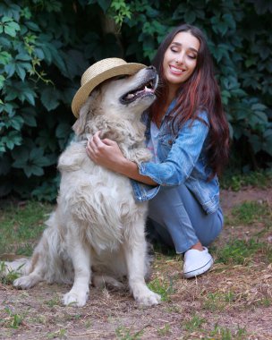 Bir şapka giyen onu komik oynayan evcil köpek Golden retriever ile genç güzel 30 yaşındaki kadın Portresi.