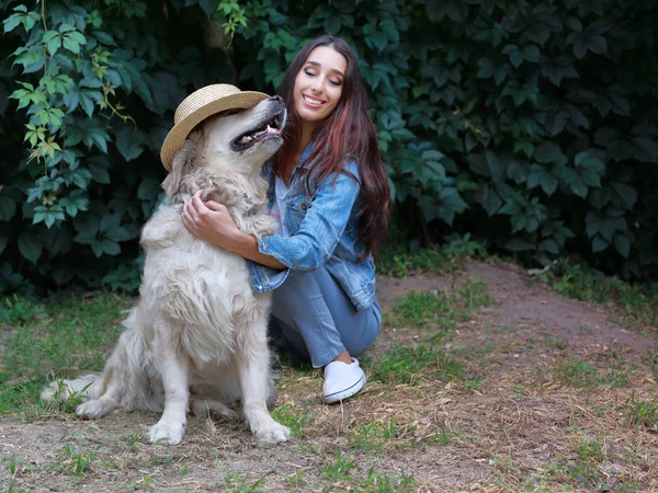 Porträt der jungen schönen 30-jährigen Frau mit ihrem lustig spielenden Hund Golden Retriever mit Hut. — Stockfoto