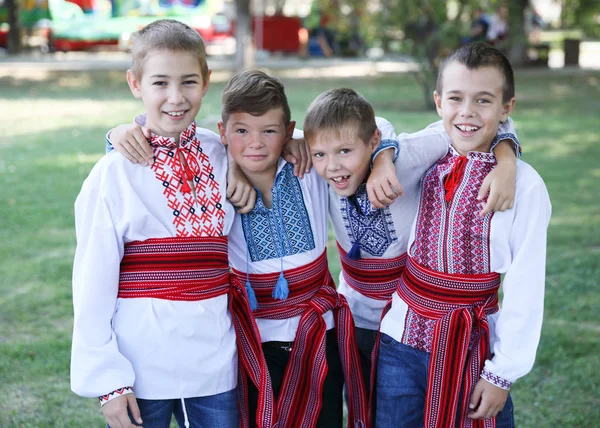 Ucrania, Pokrov - 23 de agosto de 2019: Fiesta del Día Nacional de la Bandera. Cuatro jóvenes amigos vestidos con camisas bordadas populares ucranianas se paran abrazando y riendo —  Fotos de Stock