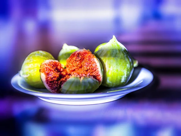 Fresh ripe figs on a plate on bright purple neon background — Stock Photo, Image