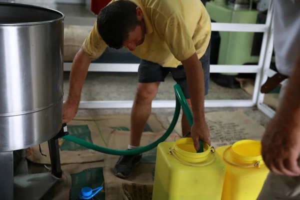 Chipre, Kyrenia - Octubre de 2019: El proceso de producción de aceite de oliva en una fábrica de aceite moderna en el norte de Chipre. Trabajador vertiendo aceite de oliva fresco en recipientes de plástico — Foto de Stock