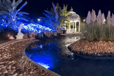 Bir şelale ve gece aydınlatma ile dekoratif yunuslar ile çardak ve yapay gölet ile güzel park. Kuzey Kıbrıs manzarası