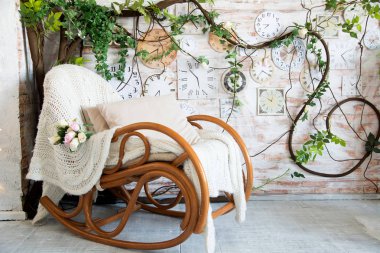 Arka plan ile yastık dalları çiçek ve duvar saatleri ile arka plan üzerinde sallanan sandalye ile. Rustik iç arka plan