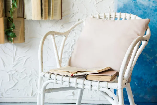 有枕头和书的威克椅子 背景与书在墙壁和花 — 图库照片
