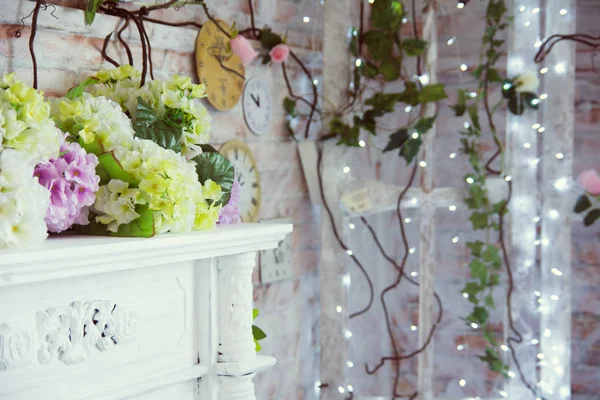 Decorative table with artificial flowers and a background of burning garlands — Stock Photo, Image