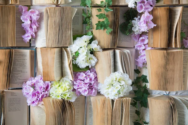 Sfondo aperto libri sulla parete e fiori artificiali viola e bianco — Foto Stock