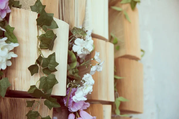 Concept background opened books on the wall and flowers of artificial purple and white — Stock Photo, Image