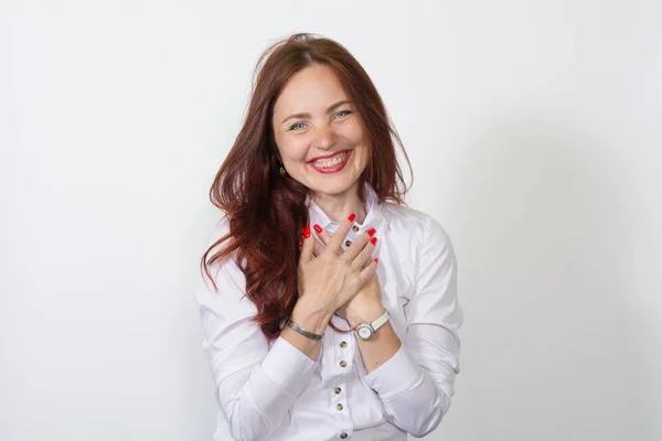 Remerciante femme aux cheveux roux heureux, portant un chemisier blanc serrant les paumes ensemble reconnaissante, appréciant geste romantique mignon, souriant — Photo