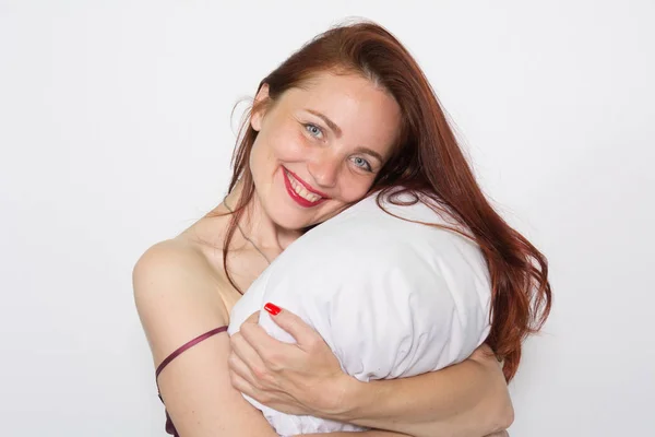 Potret tersenyum seorang wanita bersandar di atas bantal di atas latar belakang putih — Stok Foto