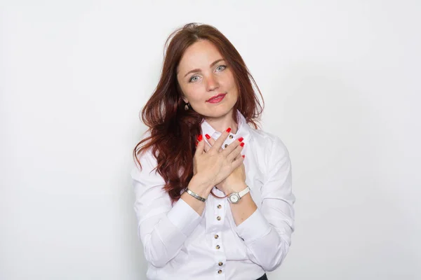 Femme aux cheveux roux dans un chemisier lumineux avec les mains jointes sur un blanc — Photo