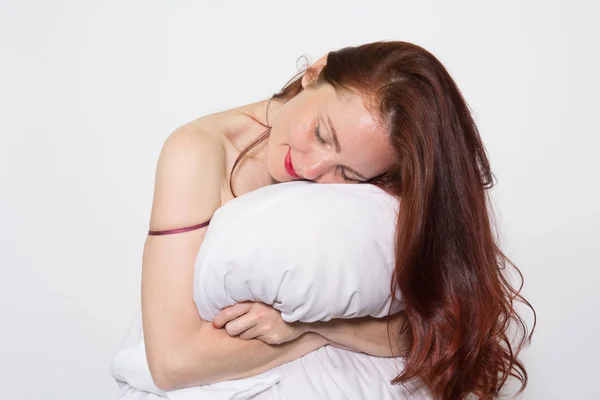 Retrato de uma mulher com os olhos fechados descansando em um travesseiro sobre fundo branco — Fotografia de Stock