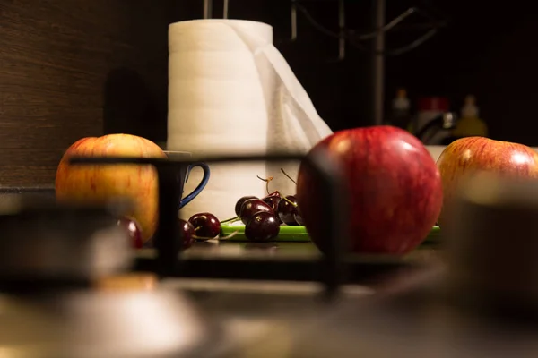 Background apples and cherries on on the kitchen table with a gas stove