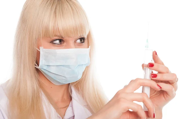 Close-up van een jonge vrouwelijke verpleegkundige in een masker met een spuit. — Stockfoto