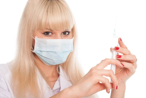 Close-up van een jonge vrouwelijke verpleegkundige in een masker met een spuit. — Stockfoto