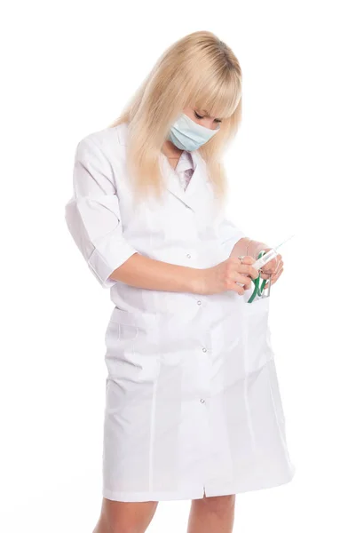Gemaskerde verpleegkundige met een spuit in haar hand en een stethoscoop. — Stockfoto