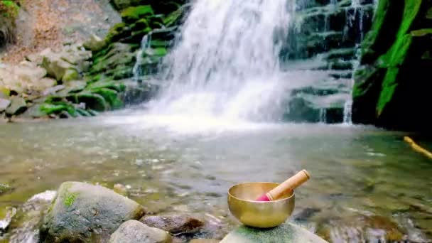 在瀑布的背景下 山溪上的石头上的喜马拉雅歌唱碗 — 图库视频影像
