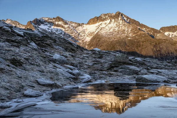 A reflection of mountains lit with the evening sun in the Tromso county, Norway