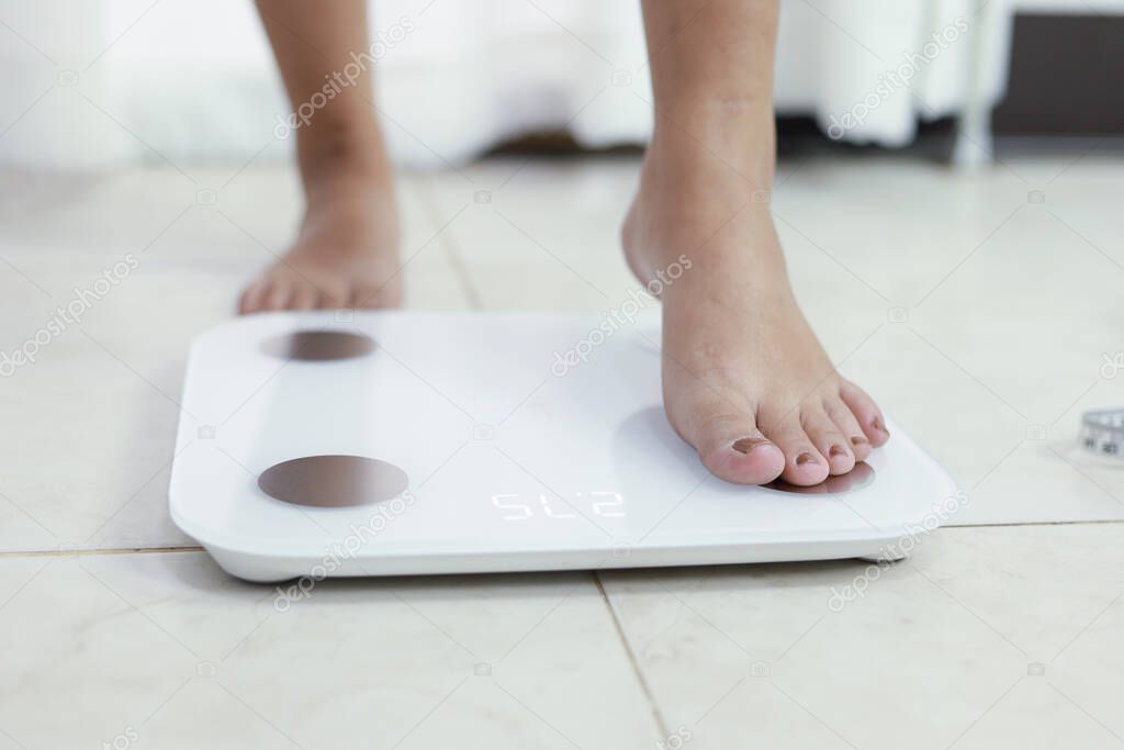 feet standing on electronic scales for weight control. Measurement instrument in kilogram for a diet control