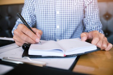 Erkek öğrenci, üniversite kampüsündeki derslere hazırlanırken taşınabilir tabletten bilgi yazar.