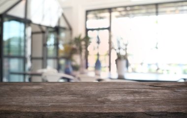 Kafenin soyut bulanık arka planının önündeki boş ahşap masa. Ürünlerinizi görüntülemek veya montajlamak için kullanılabilir. Ürünün görüntülenmesi için modelleyin