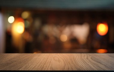 Restoranın soyut bulanık arka planının önündeki boş, siyah ahşap masa. Ürünlerinizi görüntülemek ya da montajlamak için kullanılabilir. 