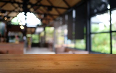 Restoranın soyut bulanık arka planının önündeki boş, siyah ahşap masa. Ürünlerinizi görüntülemek ya da montajlamak için kullanılabilir.