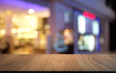 Kafenin soyut bulanık arka planının önündeki boş ahşap masa. Ürünlerinizi görüntülemek veya montajlamak için kullanılabilir. Ürünün görüntülenmesi için modelleyin