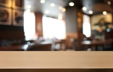 Restoranın soyut bulanık arka planının önündeki boş, siyah ahşap masa. Ürünlerinizi görüntülemek ya da montajlamak için kullanılabilir. 