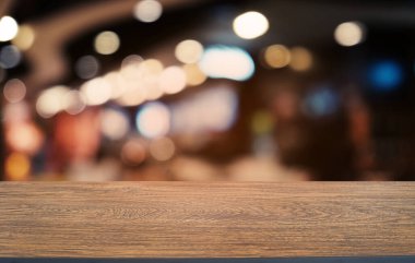Restoranın soyut bulanık arka planının önündeki boş, siyah ahşap masa. Ürünlerinizi görüntülemek ya da montajlamak için kullanılabilir.