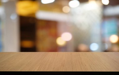 Restoranın soyut bulanık arka planının önündeki boş, siyah ahşap masa. Ürünlerinizi görüntülemek ya da montajlamak için kullanılabilir. 