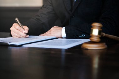 Hukuk danışmanı müvekkiline tokmak ve hukuk hukuku ile imzalanmış bir sözleşme sunar. Adalet ve avukat kavramı