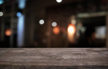 Restoranın soyut bulanık arka planının önündeki boş, siyah ahşap masa. Ürünlerinizi görüntülemek ya da montajlamak için kullanılabilir.