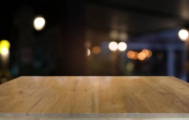 Kafenin soyut bulanık arka planının önündeki boş ahşap masa. Ürünlerinizi görüntülemek veya montajlamak için kullanılabilir. Ürünün görüntülenmesi için modelleyin