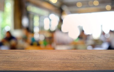 Restoranın soyut bulanık arka planının önündeki boş, siyah ahşap masa. Ürünlerinizi görüntülemek ya da montajlamak için kullanılabilir. 