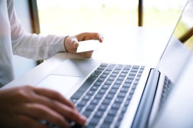 İş kadını elleri plastik kredi kartı tutuyor ve online alışveriş konsepti olan akıllı telefon kullanıyor.