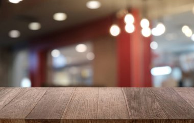 Restoranın soyut bulanık arka planının önündeki boş, siyah ahşap masa. Ürünlerinizi görüntülemek ya da montajlamak için kullanılabilir.