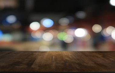 Restoranın soyut bulanık arka planının önündeki boş, siyah ahşap masa. Ürünlerinizi görüntülemek ya da montajlamak için kullanılabilir.