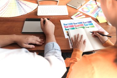 Grafik tasarımcısı dijital tablet üzerinde çalışıyor. Grafik tablet ve renk örneklerine resim çizen sanatçı