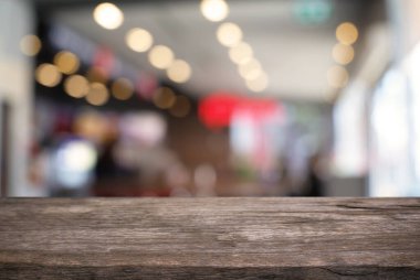 Kafenin soyut bulanık arka planının önündeki boş ahşap masa. Ürünlerinizi görüntülemek veya montajlamak için kullanılabilir. Ürünün görüntülenmesi için modelleyin