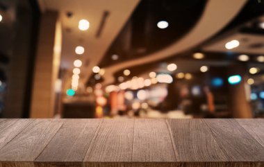 Restoranın soyut bulanık arka planının önündeki boş, siyah ahşap masa. Ürünlerinizi görüntülemek ya da montajlamak için kullanılabilir.