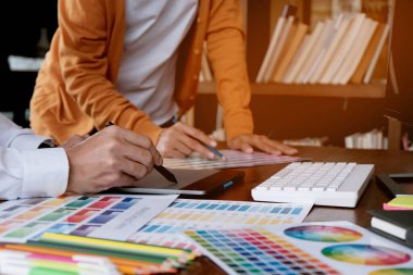 Grafik tasarımcısı dijital tablet üzerinde çalışıyor. Grafik tablet ve renk örneklerine resim çizen sanatçı