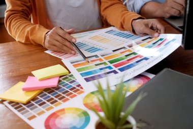 Grafik tasarımcısı dijital tablet üzerinde çalışıyor. Grafik tablet ve renk örneklerine resim çizen sanatçı