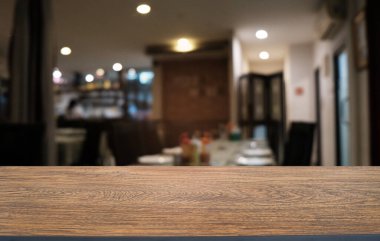 Restoranın soyut bulanık arka planının önündeki boş, siyah ahşap masa. Ürünlerinizi görüntülemek ya da montajlamak için kullanılabilir.