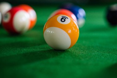Adamın eli ve Cue kolu bilardo oynuyor ya da yeşil bir bilardo masasında bilardo topu fırlatmaya hazırlanıyor. Yeşil frizde renkli bilardo topları